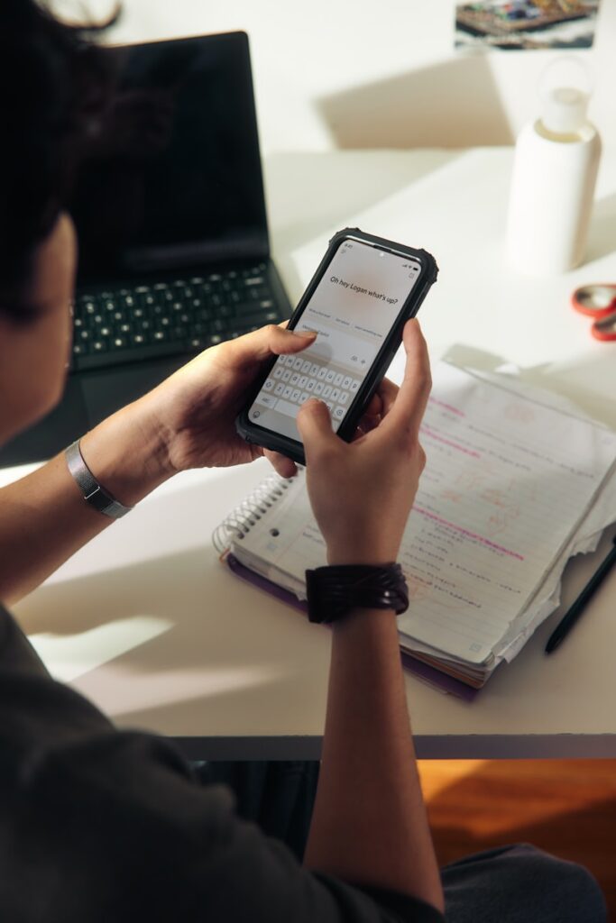 Person using a smartphone over a notebook